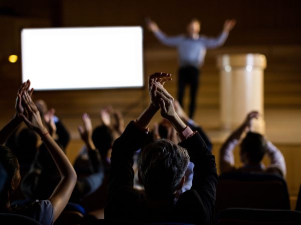 Audience applauding speaker after conference presentation at conference center